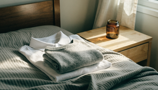 Freshly washed school uniform folded on a bed beside a small amber jar