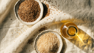 Flax and sesame seeds beside a small bottle of golden seed oil